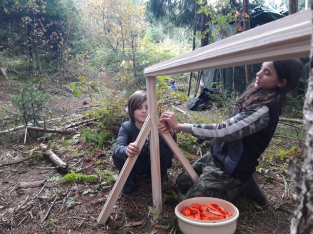 Zwei Kinder bauen am der Halterung um einen eigenen Bogen herzustellen AT