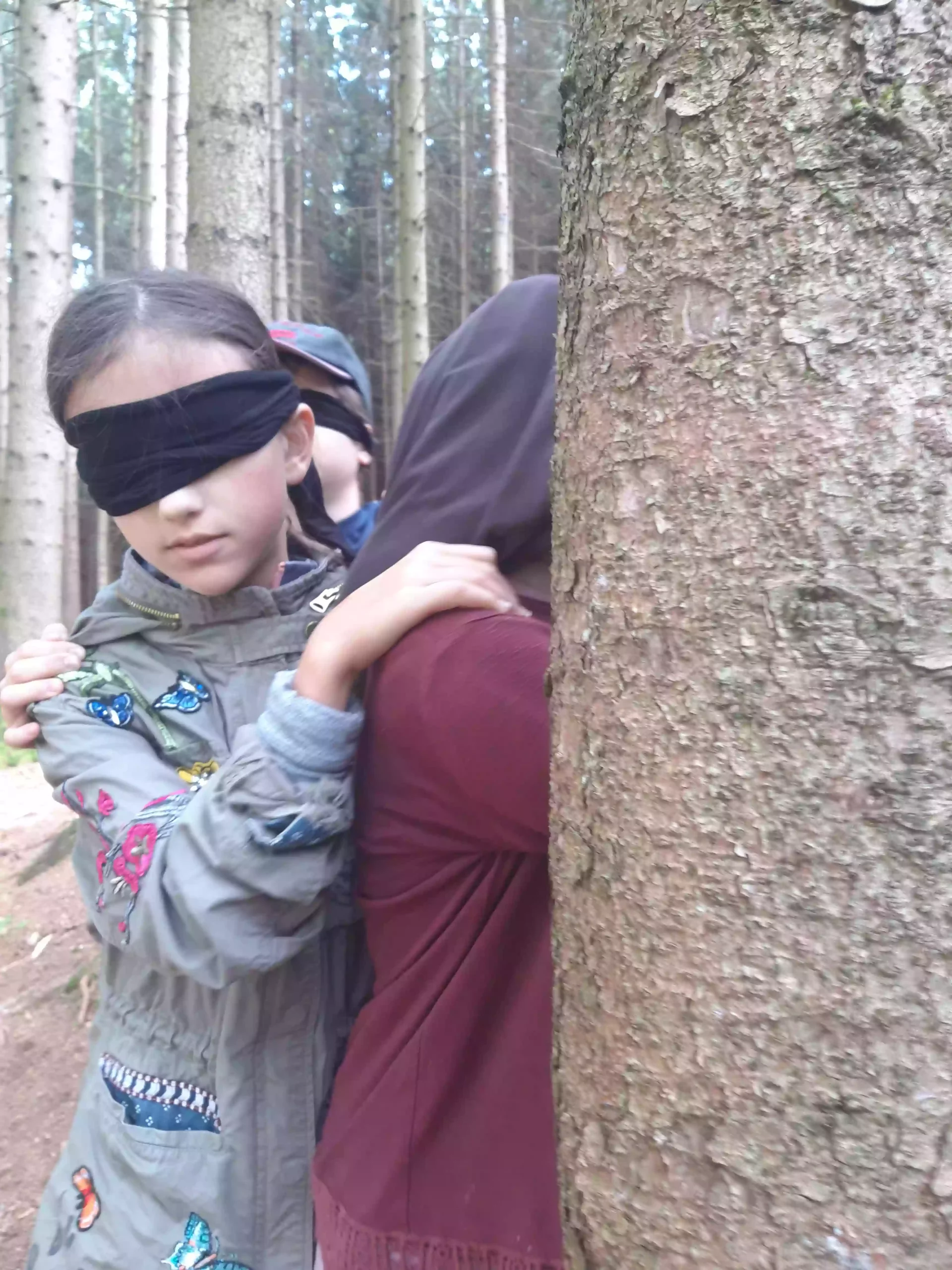 Kinder werden im Blindwalk durch den Wald geführt und erweitern so ihre Wahrnehmung.